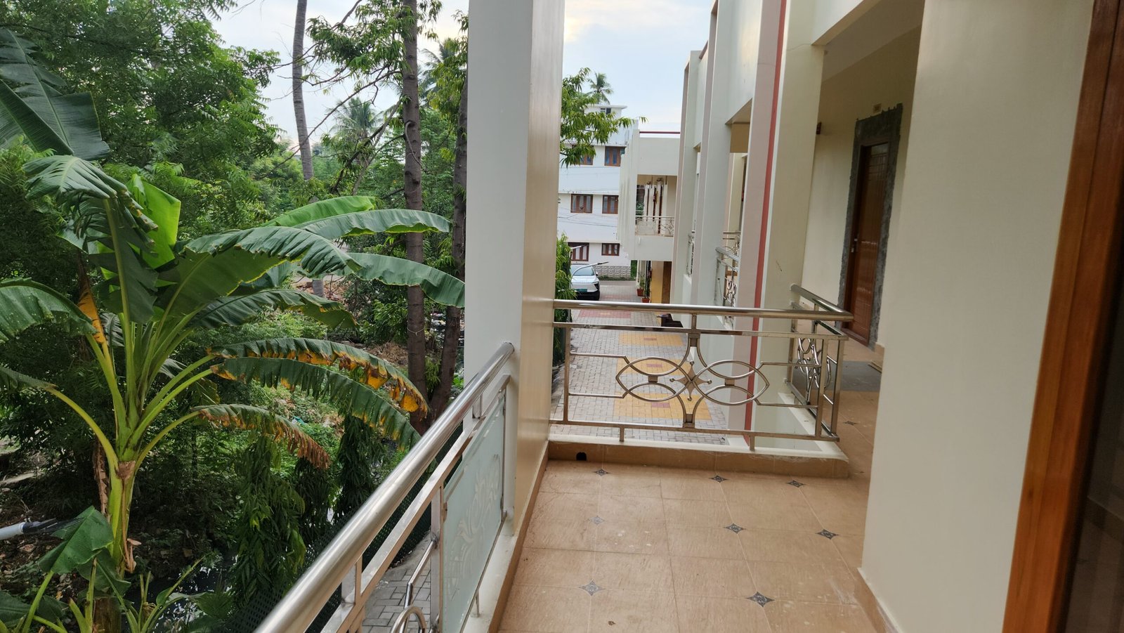 Upper-floor balcony corridor at Vishaka INN overlooking garden greenery in Kumbakonam